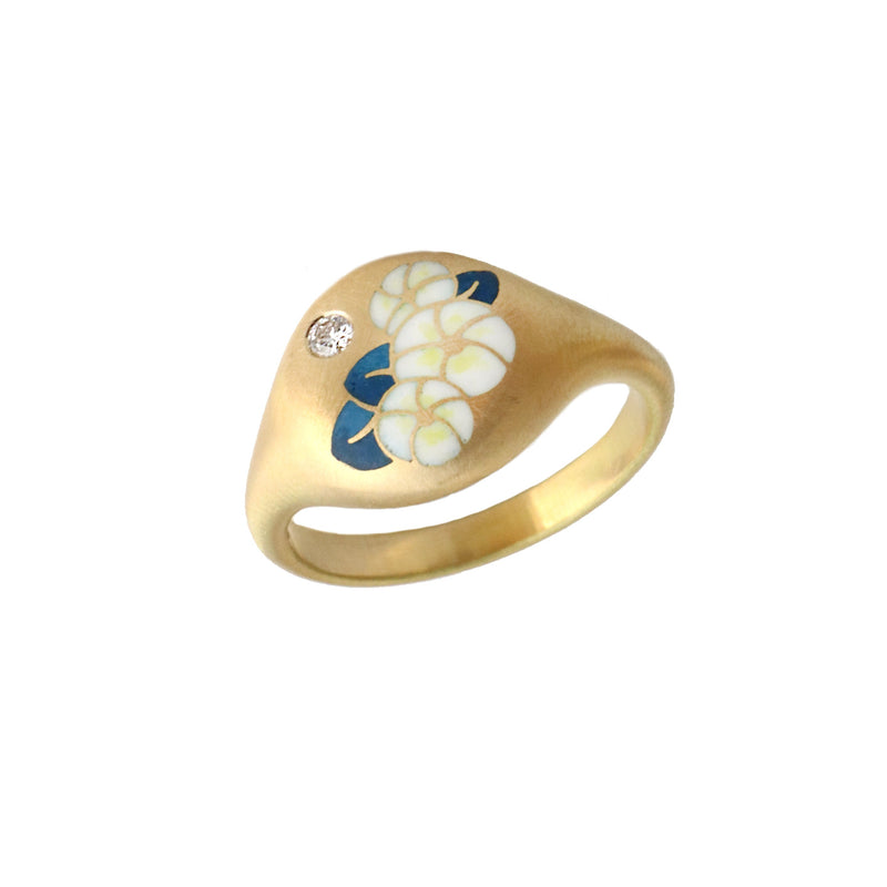 Gold signet ring with white and blue floral design and diamond on a white background