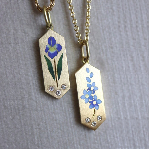 Two gold pendants with floral designs on a gray background