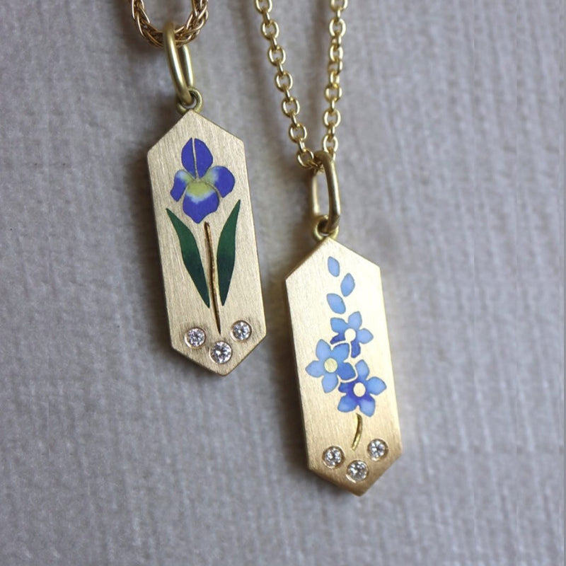 Two gold pendants with floral designs on a gray background