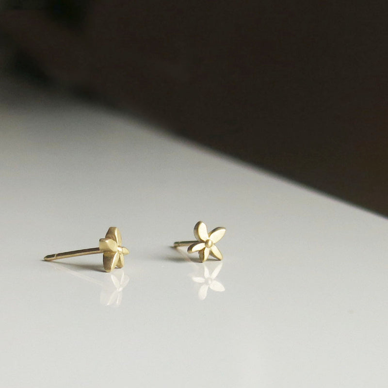 Gold small flower earring studs on a table